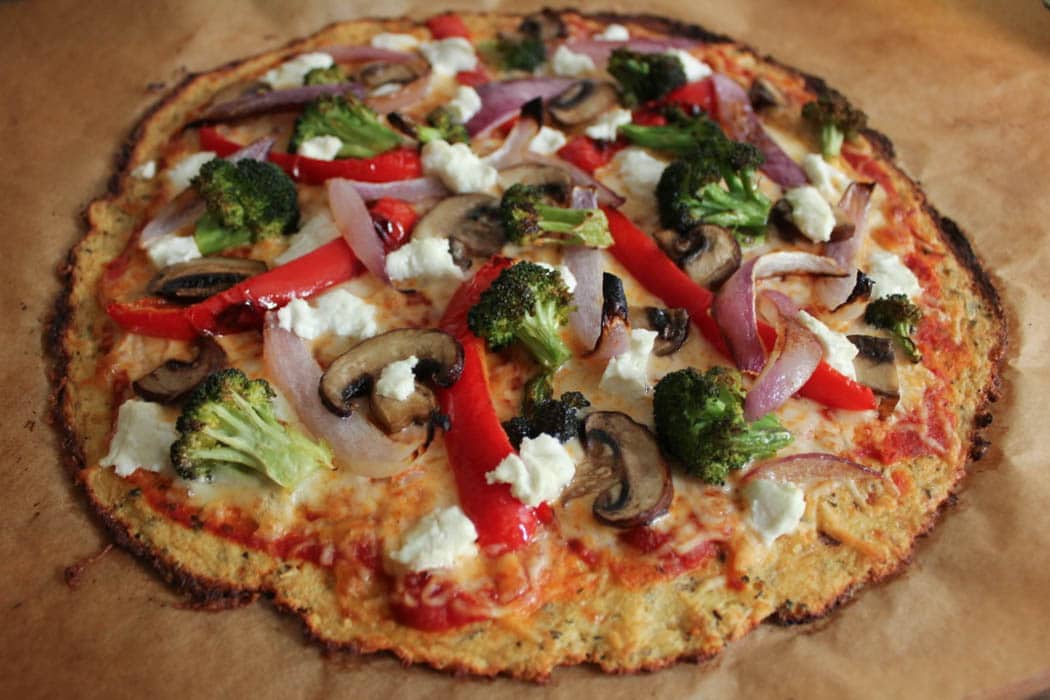 Baked cauliflower pizza crust with roasted vegetables and goat cheese.