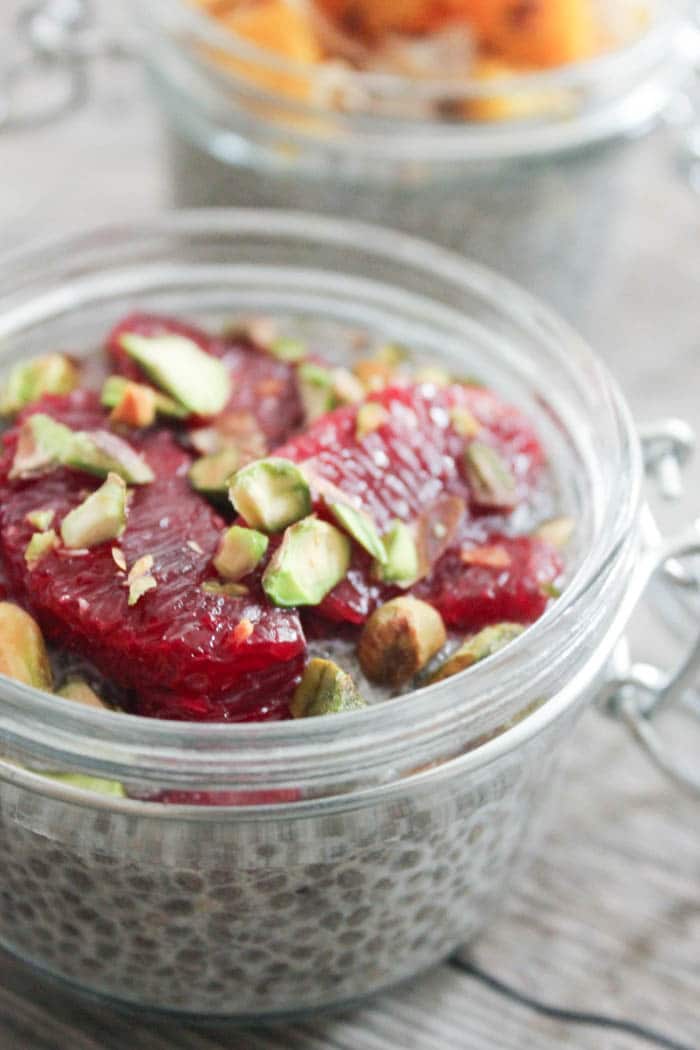 Close up of vegan chia seed pudding topped with blood orange segments and pistachios.